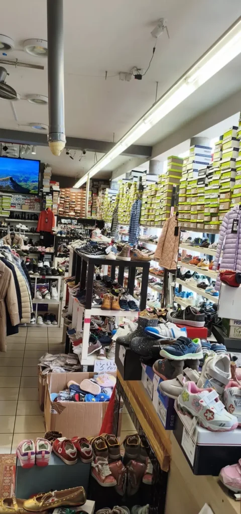 ممر في المتجر فيه صناديق أحذية أطفال ورفوف مليئة بالعلب في متجر أوتليت شوسور بروكسل بحي الماروليس