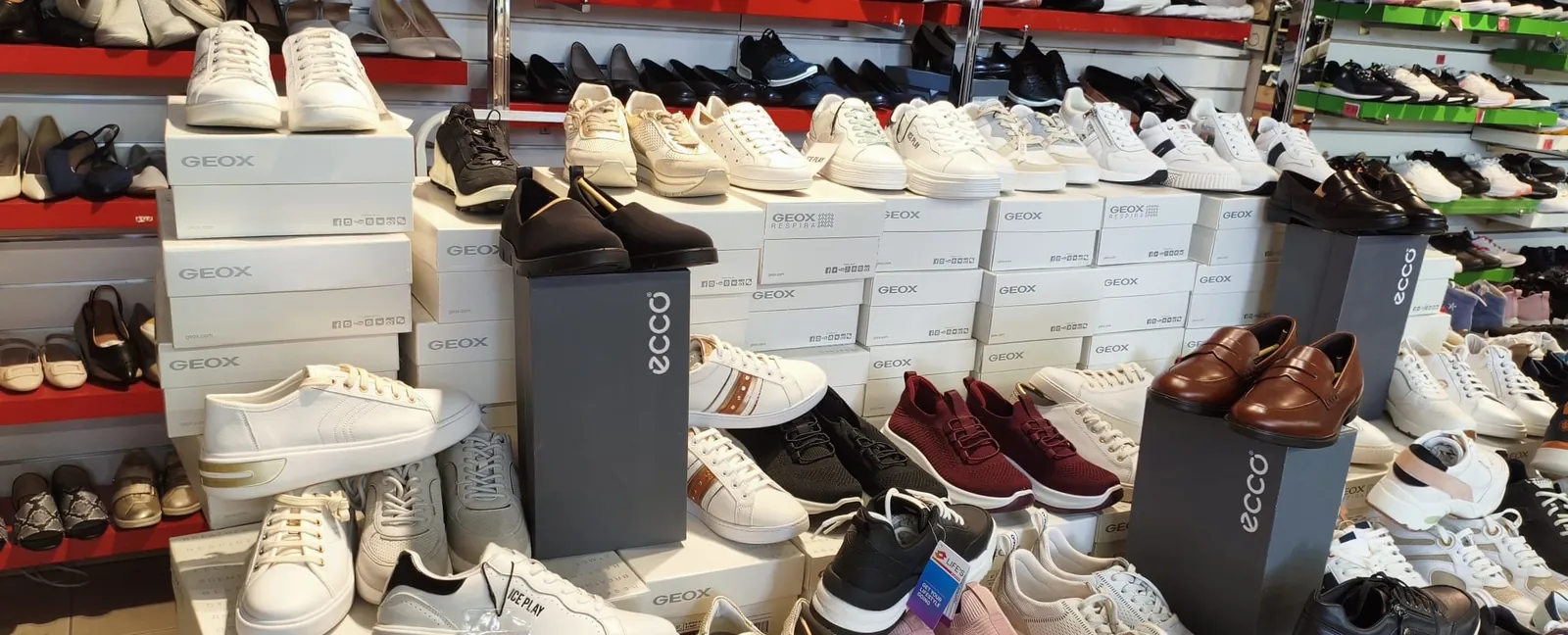 أحذية رياضية بيضاء وعنابية على علب إيكو (Ecco) في متجر Outlet Chaussures Bruxelles
